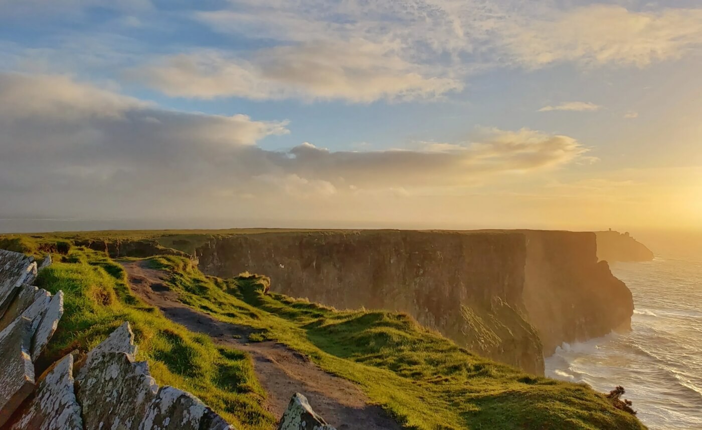 Paesaggio estivo sulle scogliere irlandesi, con il sole che illumina l’oceano.