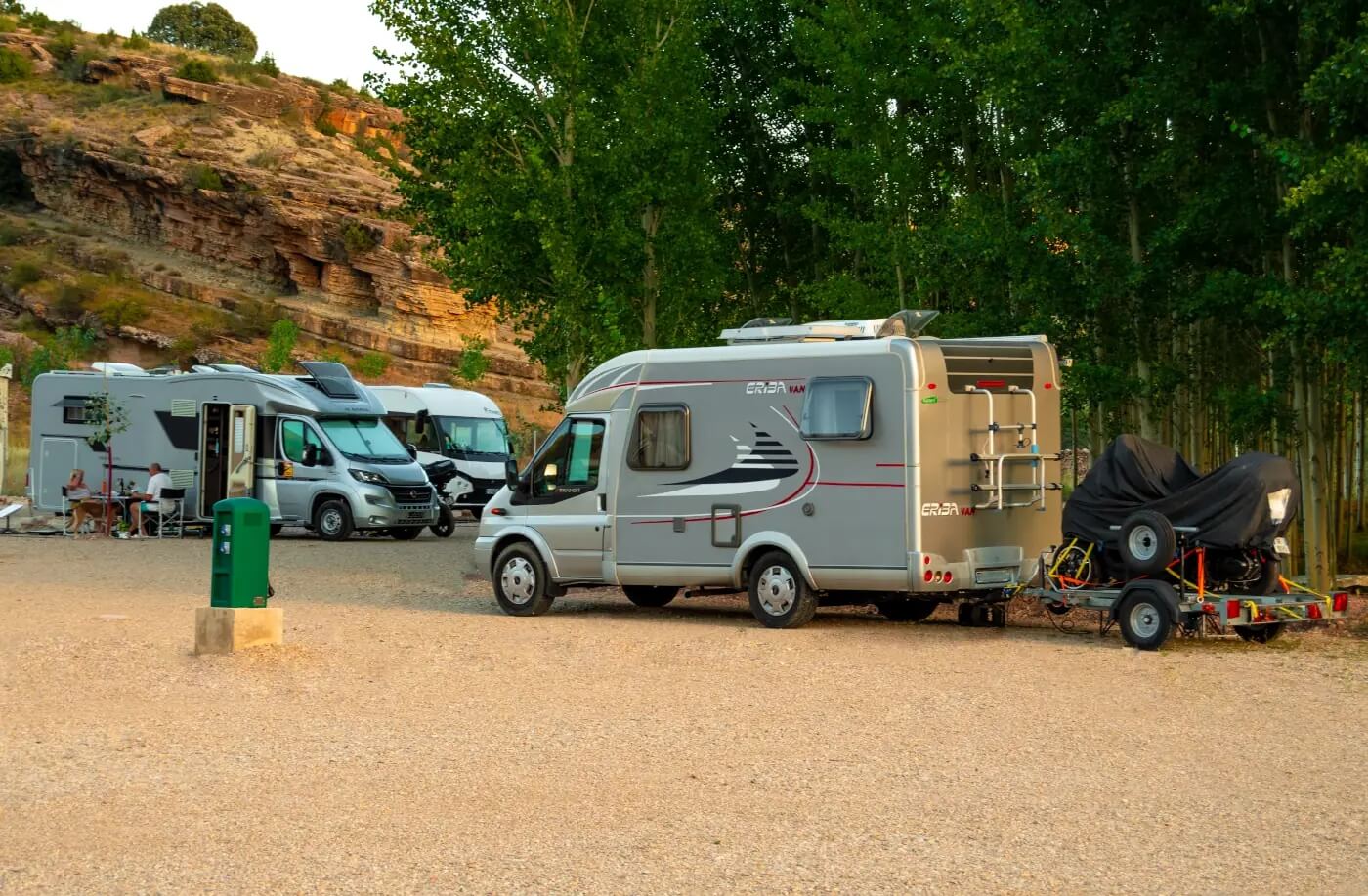 Autocaravanas estacionadas entre árboles y roca en el área de Albarracín