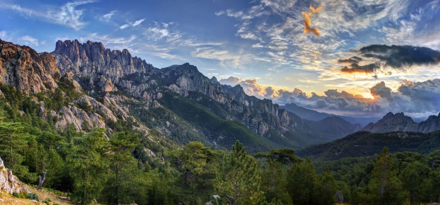 Panorama montagneux en Corse avec forêts et crêtes.