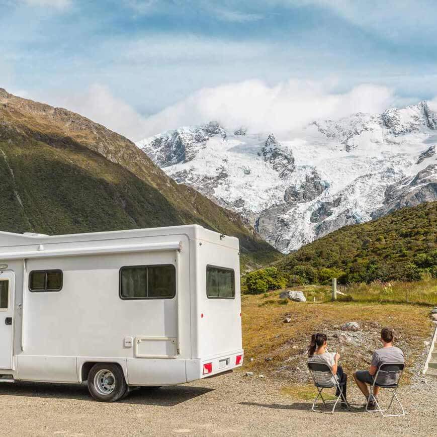 deux personnes à côté d'un camping-car de location en Nouvelle-Zélande