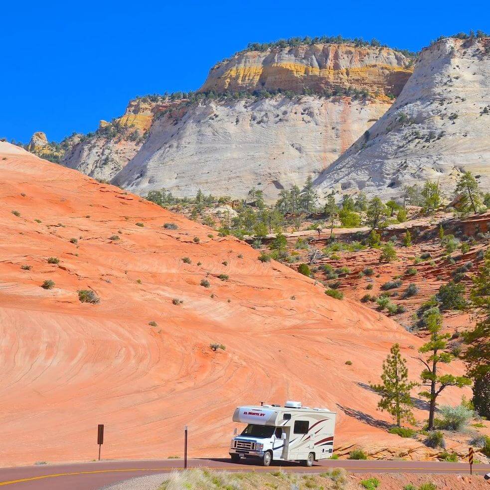 Rented RV driving along Utah's scenic highway with vibrant red rock formations.