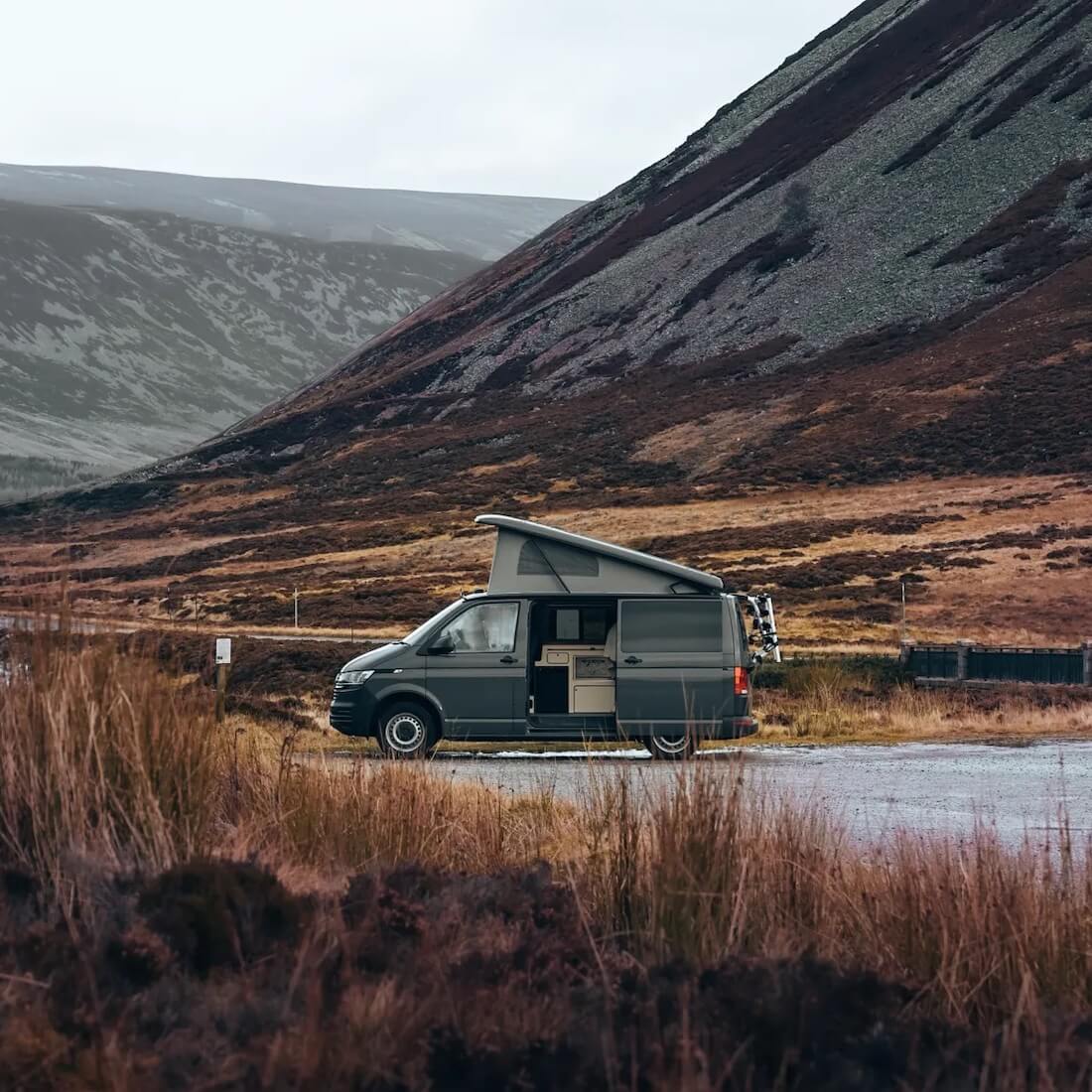 Camper auf einem Parkplatz vor den kargen Hängen des Cairngorms-Nationalparks in Schottland